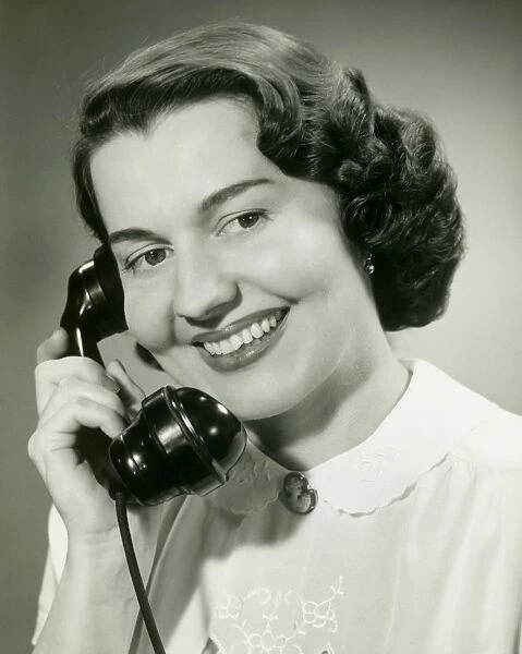 Woman talking on phone, close-up, studio shot