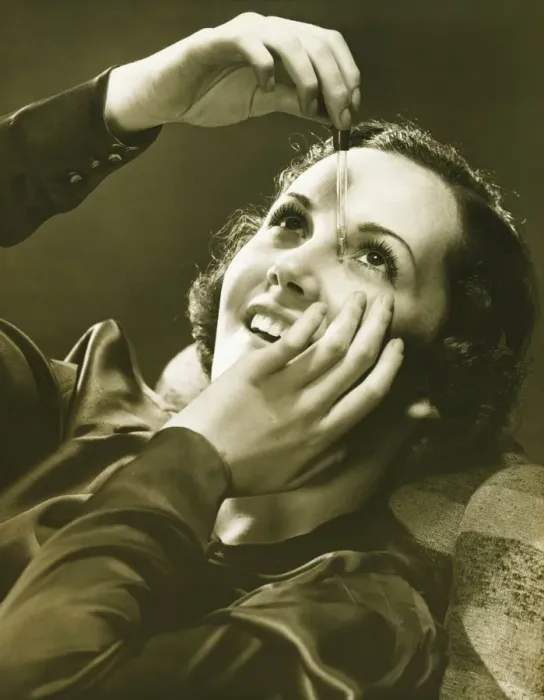 Framed Print : Woman using eye drop in studio, (B&W)