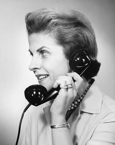 Woman using telephone, (B&W), close-up