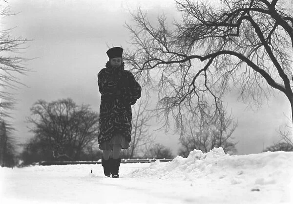 Woman walking on snow covered road, (B&W), low angle view