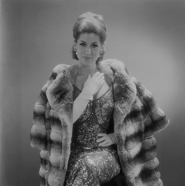 Woman wearing fur coat sitting against grey background