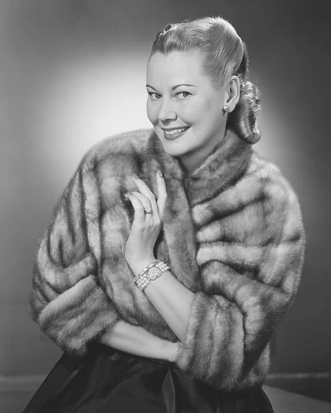 Woman wearing fur jacket posing in studio (B&W), portrait