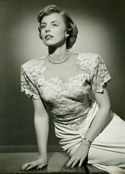 Woman wearing lace evening gown posing in studio, (B&W), (Portrait)