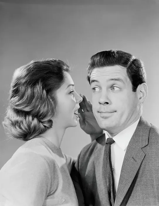 Framed Print : Woman whispering into man's ear, man pulling funny face Framed Print : Woman whispering into man's ear, man pulling funny face