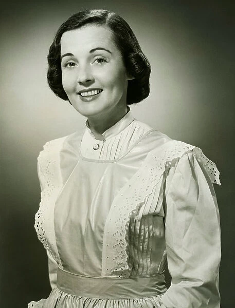 Woman in white apron posing in studio, (B&W), (Portrait)