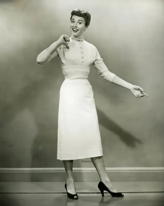 Framed Print : Woman in white dress pointing to herself in studio, (B&W), portrait Framed Print : Woman in white dress pointing to herself in studio, (B&W), portrait