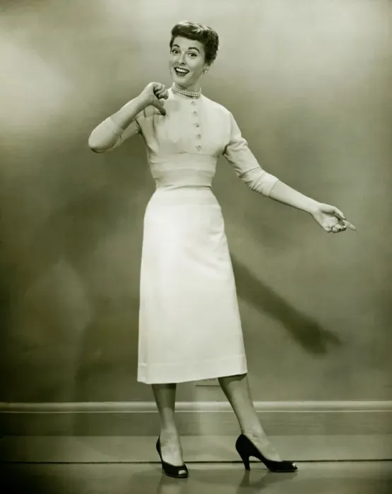 Framed Print : Woman in white dress pointing to herself in studio, (B&W), portrait Framed Print : Woman in white dress pointing to herself in studio, (B&W), portrait