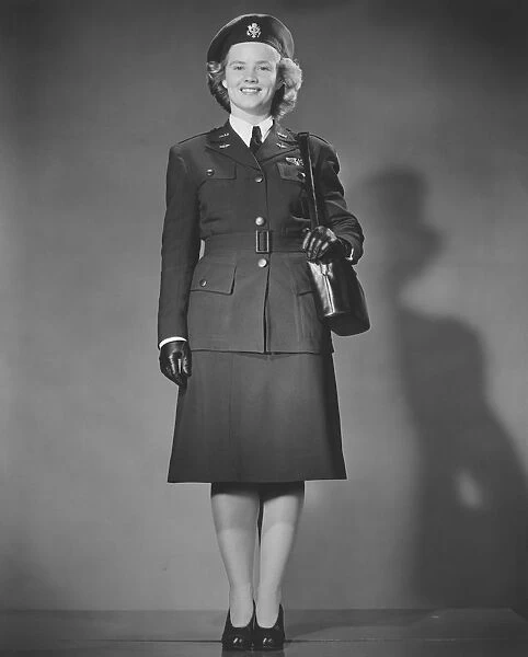 Woman in World War II military uniform posing in studio (B&W), portrait