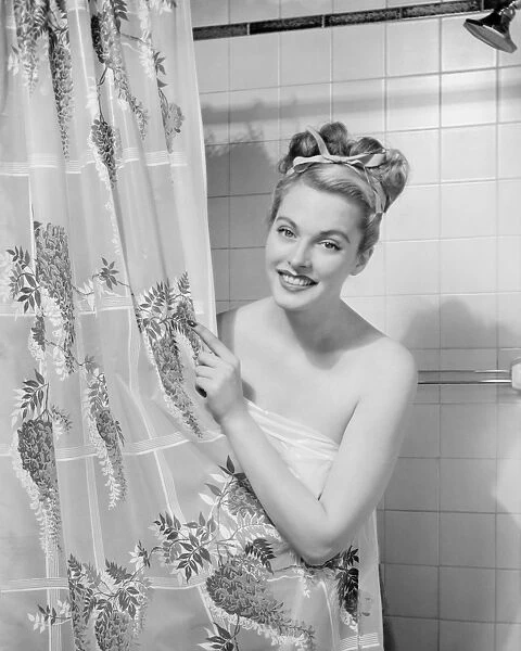 Woman wrapped in towel peeping through shower curtain (B&W), portrait