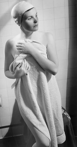 Woman wrapped in towel standing in bathroom (B&W)