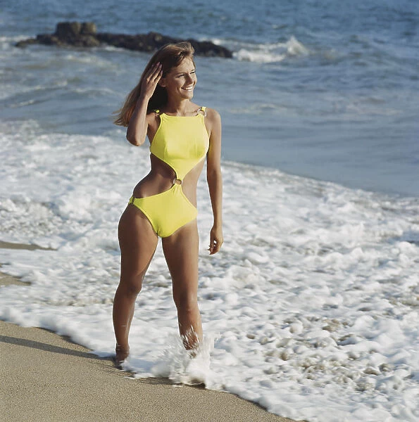 Woman in yellow swimwear standing on beach, smiling