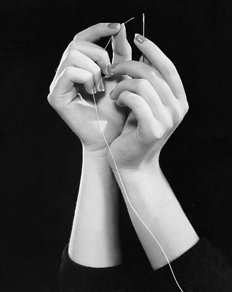 Womans hands threading needle