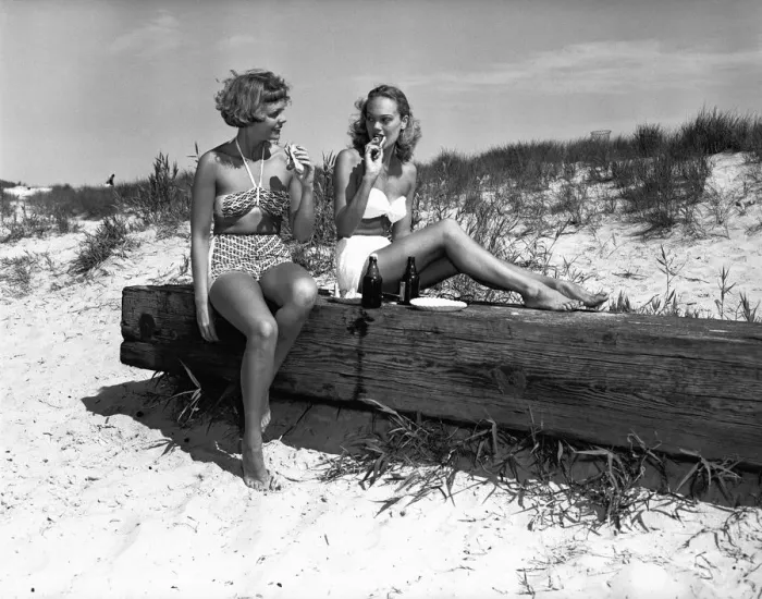 Framed Print : Two women in bikini eating snack on beach, (B&W) Framed Print : Two women in bikini eating snack on beach, (B&W)