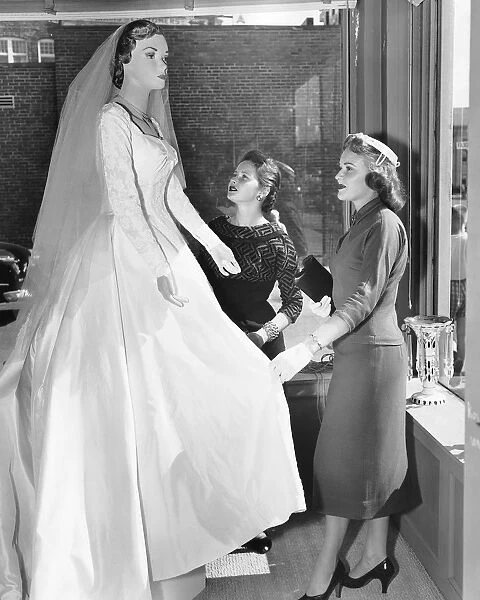 Two women looking at wedding dress on mannequin