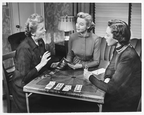 Three women playing cards at home, (B&W)