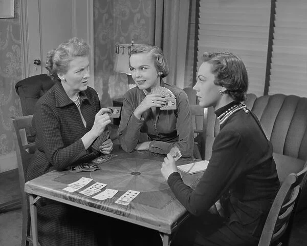 Three women playing cards in living room