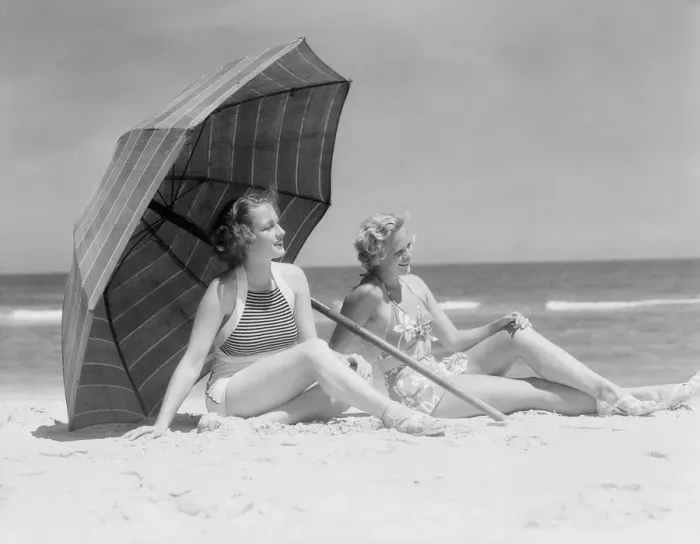 Framed Print : Two women sitting on beach under parasol Framed Print : Two women sitting on beach under parasol