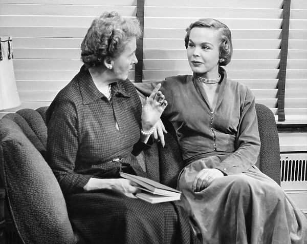 Two women sitting on couch, talking, (B&W)