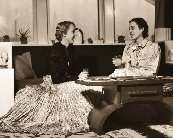 Framed Print : Two Women Sitting on Sofa with Drinks, Chatting Framed Print : Two Women Sitting on Sofa with Drinks, Chatting