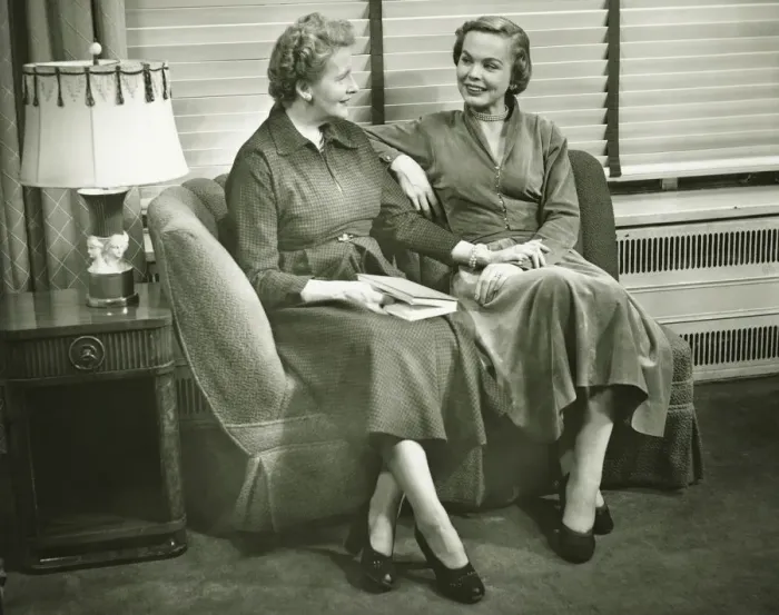 Framed Print : Two women sitting on sofa, talking, indoors, (B&W) Framed Print : Two women sitting on sofa, talking, indoors, (B&W)