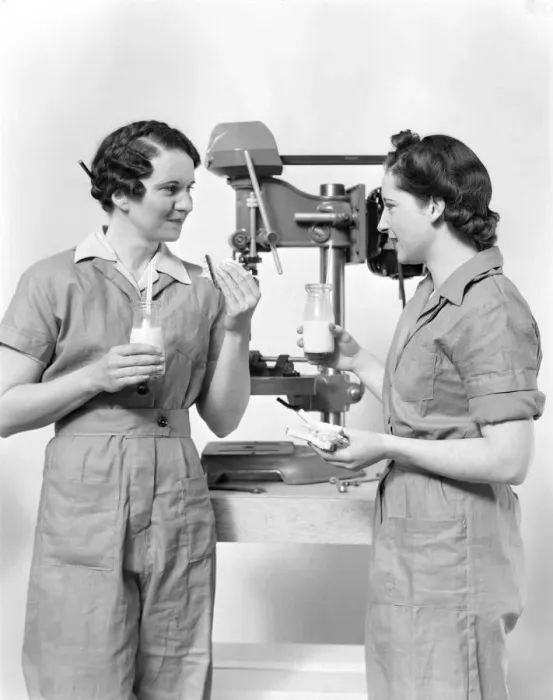 Framed Print : Two women workers standing near drill press, eating sandwich and drinking milk Framed Print : Two women workers standing near drill press, eating sandwich and drinking milk