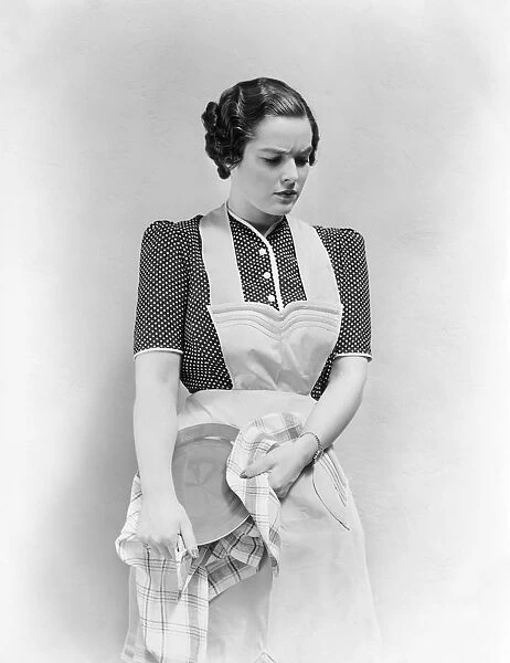 Worried woman in apron, drying dish