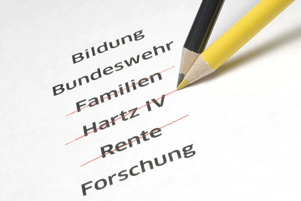 A yellow and a black pencil crossing out the letterings Familien, Hartz IV and Rente, German for families, Hartz IV, a German unemployment benefit, and pension, symbolic image for the policy of economy measures of the Conservative Parties in Germany