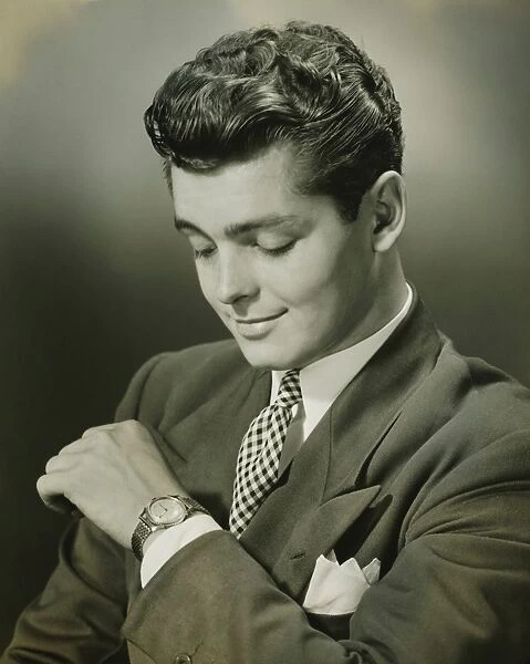 Young businessman checking time on watch, (B&W), close-up