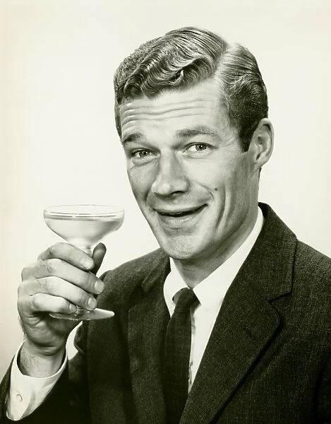 Young businessman holding wine glass, (B&W), portrait