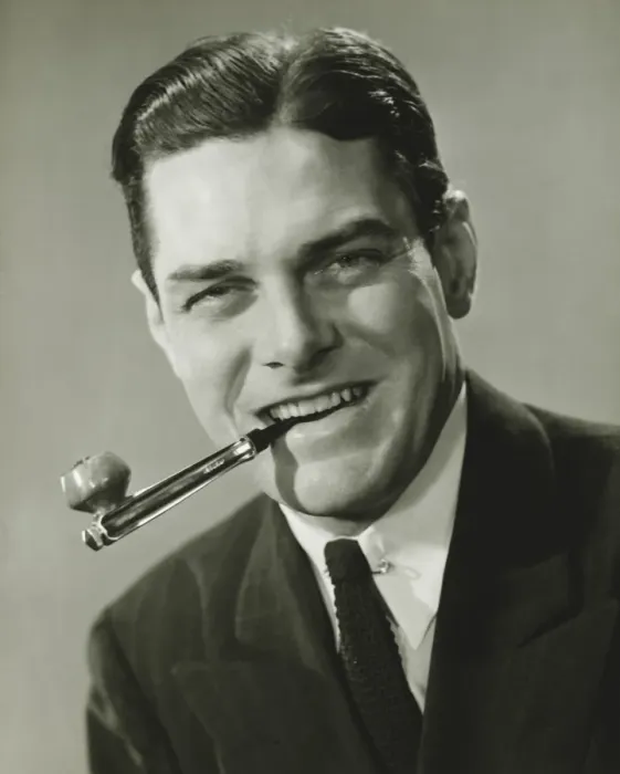 Framed Print : Young businessman in studio holding pipe in teeth, smiling, (B&W), portrait Framed Print : Young businessman in studio holding pipe in teeth, smiling, (B&W), portrait