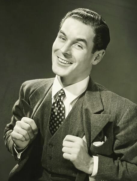 Young businessman in studio smiling, (B&W), portrait