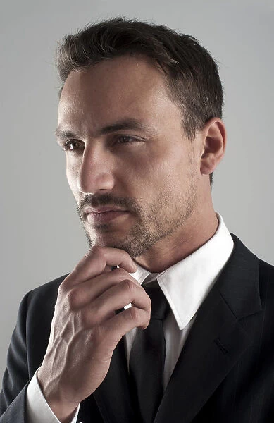 Young businessman wearing a suit with his hand on his chin, pensive, portrait