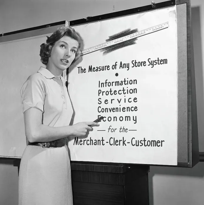 Framed Print : Young career woman giving business presentation, pointing at poster
