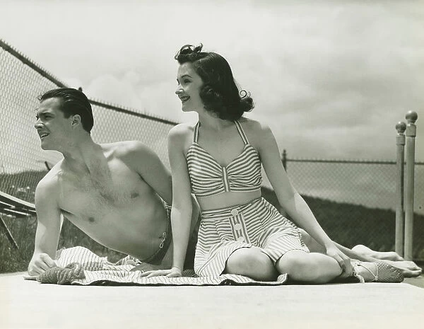 Young couple in beachwear relaxing outdoors, (B&W)