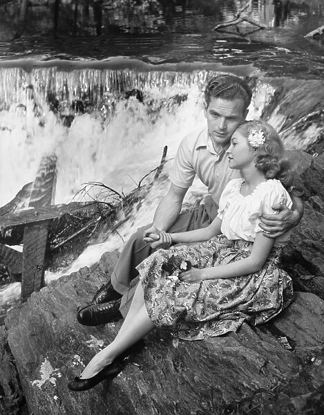 Young couple embracing near waterfall, (B&W)