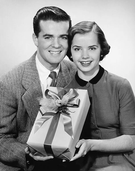 Young couple holding present, posing, (B&W)