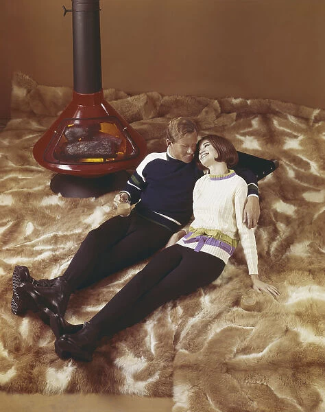 Young couple leaning on fur blanket near fireplace