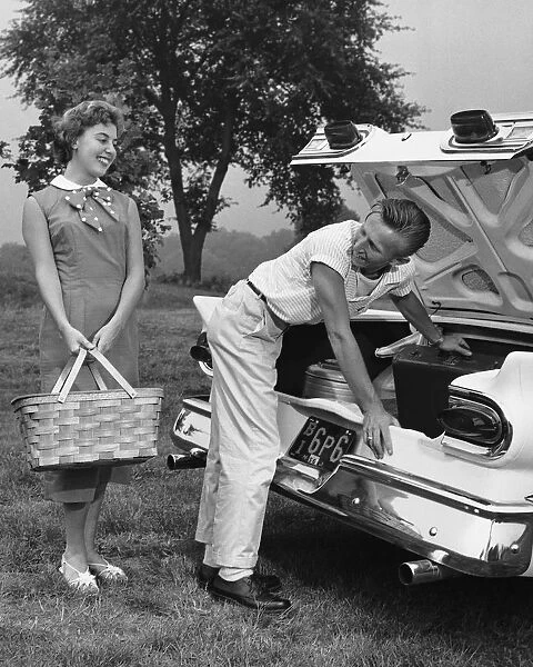 Young couple loading trunk of car for picnic
