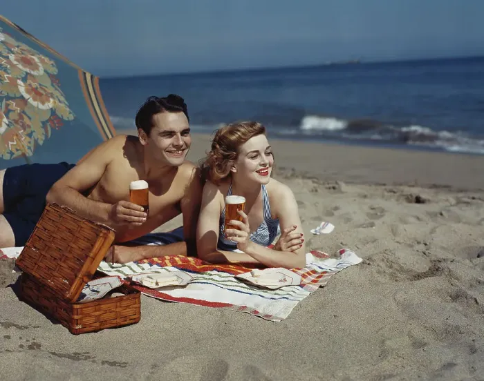 Framed Print : Young couple lying on beach with beer, smiling Framed Print : Young couple lying on beach with beer, smiling