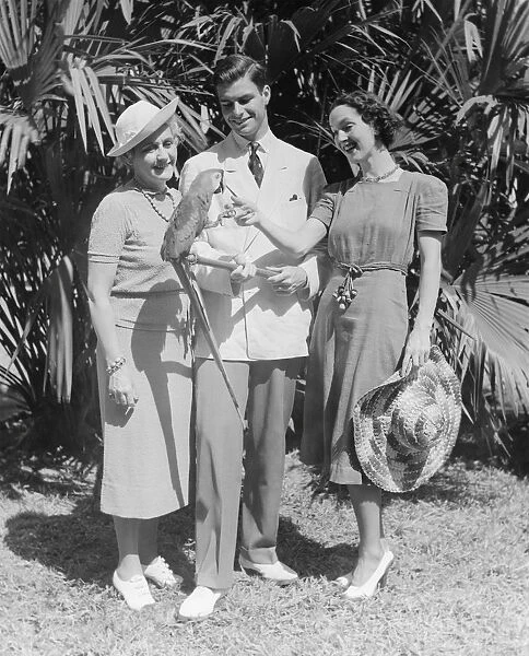 Young couple and mature woman looking at parrot (B&W)