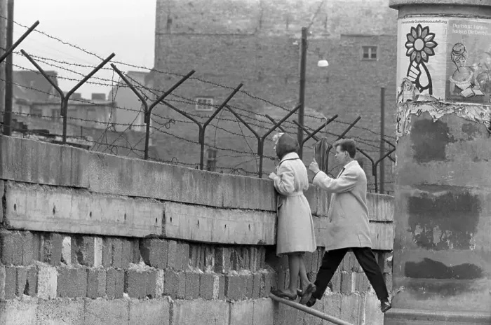 Framed Print : Young Couple Peers Over Berlin Wall Framed Print : Young Couple Peers Over Berlin Wall