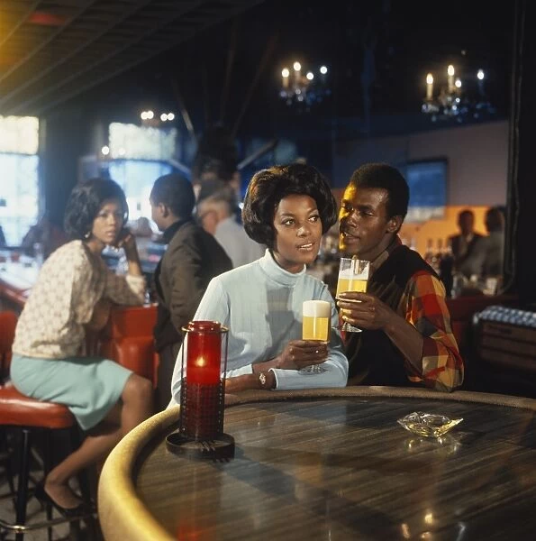 Young couple sitting at table holding glass of beer