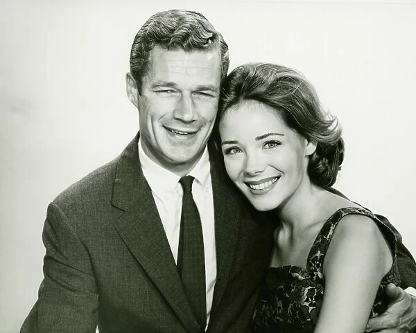 Young couple smiling, posing in studio, (B&W), portrait