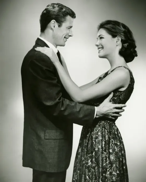 Framed Print : Young couple standing face to face, smiling, in studio, (B&W)