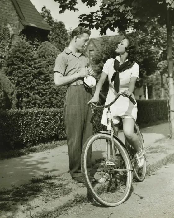 Framed Print : Young couple talking on street, woman on bicycle, (B&W)