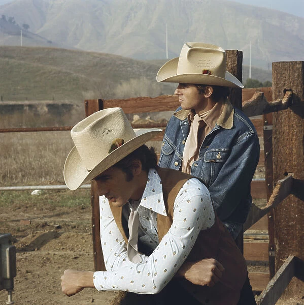 Young cowboys leaning on fence