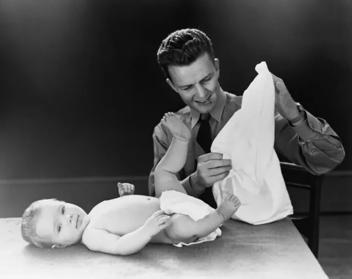 Framed Print : Young father with baby lying on table, trying to figure out how to put on diaper. (Photo by H Framed Print : Young father with baby lying on table, trying to figure out how to put on diaper. (Photo by H