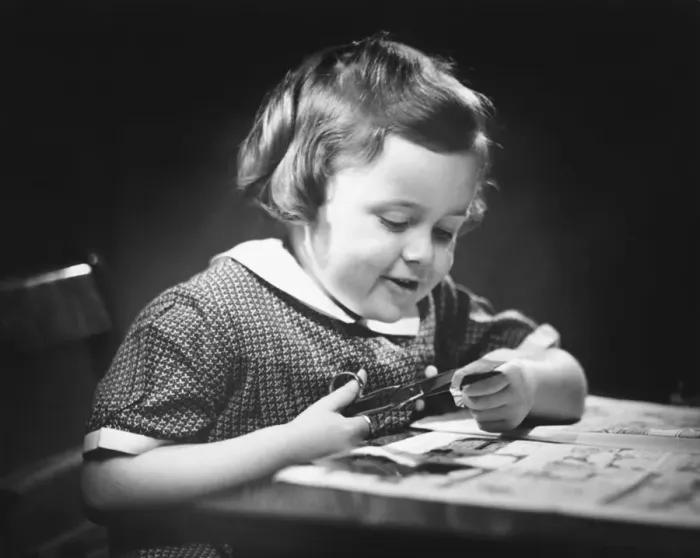Framed Print : Young girl (4-5) at table cutting paper with scissors, (B&W), close-up Framed Print : Young girl (4-5) at table cutting paper with scissors, (B&W), close-up