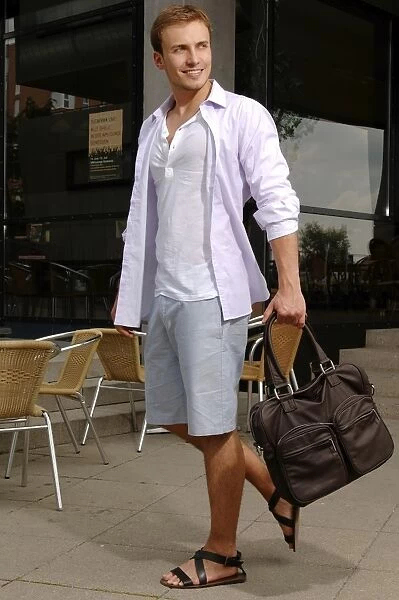 Young man with a bag wearing shorts and sandals, shopping spree