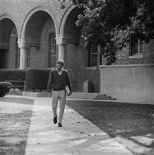 Young man with books walking on campus